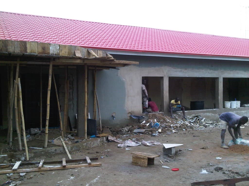 Our Place building during construction with scaffolding, unfinished walls, and a red roof