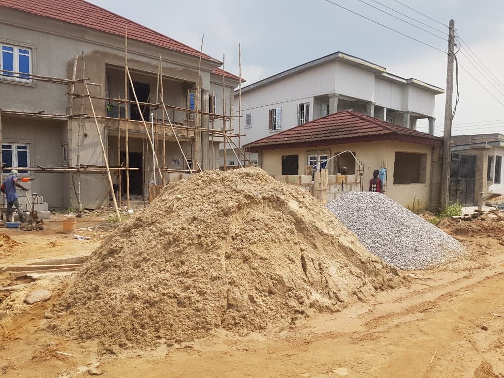 Residential renovation site with timber scaffolding and piles of sand and gravel